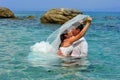 Bride & groom kissing in the clear blue sea water Royalty Free Stock Photo