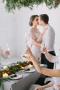 Bride And Groom kissing and Enjoying Meal At Wedding Reception. Guests drink champagne at the wedding table decorated Royalty Free Stock Photo