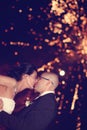 Bride and groom kissing with fireworks in background