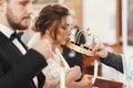 Bride and groom kissing golden crowns from priest hand during we