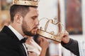 Bride and groom kissing golden crowns from priest hand during we