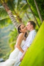 Bride and groom kissing on the lawn in summer against the palm trees Royalty Free Stock Photo