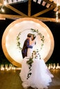 Bride and a groom kissing, standing behind their rustic wedding cake on banquet. Rustic wedding reception outdoors in Royalty Free Stock Photo