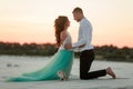 Bride and groom kneel and look at each other next to owl in desert. Royalty Free Stock Photo