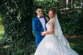 The bride and groom laugh and joke with each other, posing against the background of greenery. Royalty Free Stock Photo