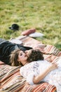 Bride and groom lie on a motley bedspread on a green grass Royalty Free Stock Photo