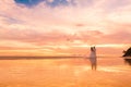 Bride and groom with long veil on tropical beach at sunset. Wedding and honeymoon in the tropics. Royalty Free Stock Photo