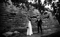 Bride and groom look gorgeous standing behind an old wall of a c Royalty Free Stock Photo