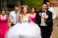 Bride and groom look happy walking in the park with friends