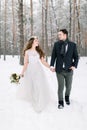 Bride and groom are looking each other and walking in the winter forest. Close-up. Winter wedding ceremony. Royalty Free Stock Photo