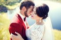 Bride and groom, lovely couple, cuddling on waterfront, photo shoot after wedding ceremony. Stylish man with mustache. Royalty Free Stock Photo