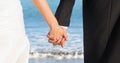 Bride and groom lower bodies holding hands against blurry beach shore Royalty Free Stock Photo