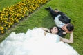 Bride and groom lying down on lawn with flowers Royalty Free Stock Photo