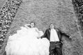 Bride and groom lying on lawn with flowers bw Royalty Free Stock Photo