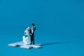 Bride and groom married miniature people stand above white puzzle jigsaw, isolated cut out on a blue background. Wedding plan