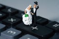 Bride and groom miniature people stand above calculator, on a white background. Wedding plan budget and financial concept