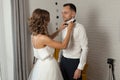The bride and groom in the morning at the hotel on a wedding day. Dressing a newly-married couple Woman help fixing bowtie to