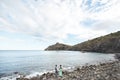 The bride and groom on nature in the mountains near the water. Suit and dress color Tiffany. Stand on the beach holding