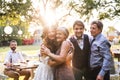 Bride, groom with parents posing for the photo at wedding reception outside in the backyard. Royalty Free Stock Photo
