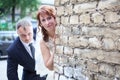 Bride and groom peek around corner of brick wall, copyspace Royalty Free Stock Photo
