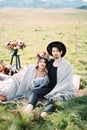 Bride and groom in plaids are sitting on a colorful bedspread Royalty Free Stock Photo