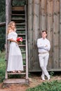 Bride and groom are posing near the old wooden house with a staircase Royalty Free Stock Photo