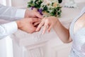 bride and groom put on each other rings, a white shirt and a shiny wedding dress, light background, a ceremony in the studio, hand Royalty Free Stock Photo