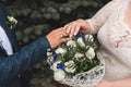 The bride and groom put their hands on the wedding bouquet of flowers of white roses, close-up of tenderness and romance Royalty Free Stock Photo