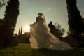 Bride and groom running away at sunset, garden wedding at sunset