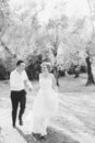 Bride and groom running through the olive grove holding hands and laughing, black and white photo