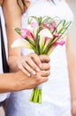 Bride and groom's hands with bouquet of callas