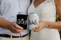 Excited Caucasian Bride & Groom Posing while Showing Off Custom Black and White Drink Beverage Koozies on their Big Wedding Day