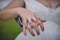 Bride and groom showing wedding rings, close up. Young married couple holding hands on their wedding day outdoors. Royalty Free Stock Photo