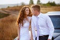 The bride and groom sit on the car in the field at the wedding day Royalty Free Stock Photo