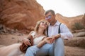 Bride and groom sit and hold hands in canyon. Closeup.