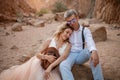 Bride and groom sit and smile in canyon on sand on background of rocks. Closeup. Royalty Free Stock Photo