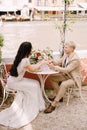 The bride and groom are sitting at tables on the banks of the Grand Canal and holding hands in Venice, Italy. The most