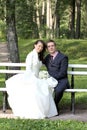 Bride and groom sitting on bench in park