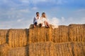 The bride and groom on the background of the sky are sitting on a large haystack Royalty Free Stock Photo
