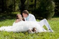 Bride and groom sitting at green grass