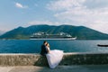 The bride and groom are sitting hugging on a stone fence of the pier, the bride is leaning on the groom, cruise liner Royalty Free Stock Photo