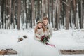 Bride and groom are sitting on the log in the winter forest. Close-up. Winter wedding ceremony. Royalty Free Stock Photo