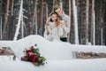 Bride and groom are sitting on the log in the winter forest. Close-up. Winter wedding. Soft focus on the couple Royalty Free Stock Photo