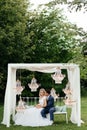 Bride and groom sitting on the white bench with pillows in the arch from the lustres. Embracing newlywed Royalty Free Stock Photo