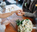 The bride and groom are sitting at a wooden table in a cafe, reaching out with their hands to each other Royalty Free Stock Photo