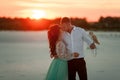 Bride and groom with small owl in hands are standing, huging and kissing on background of sunset. Royalty Free Stock Photo