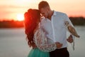 Bride and groom with small owl are standing and huging on background of sunset. Closeup. Royalty Free Stock Photo