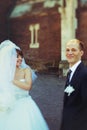 Bride and groom smile standing apart behind an old cathedral Royalty Free Stock Photo