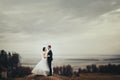 Bride and groom stand on the hill with great autumn landscape be
