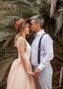 Bride and groom stand and hold hands on background of palm trees. Royalty Free Stock Photo